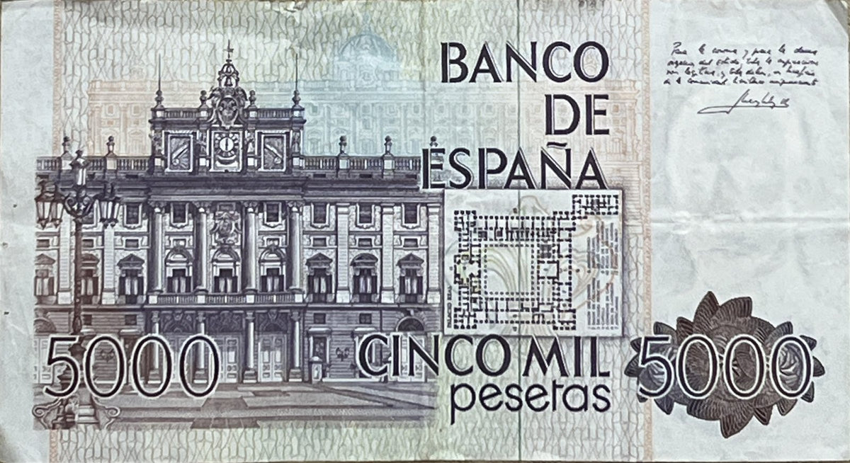 Back view of a 1979 Spain 5000 Pesetas banknote showing the façade and floor plan of the Royal Palace of Madrid with a handwritten quotation signed by the King.