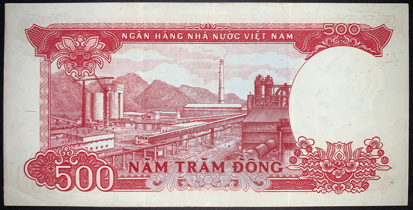 Reverse of an authentic Vietnam 500 Đồng banknote 1985 P-99 depicting an industrial factory complex with smokestack, processing facilities, and mountainous landscape, surrounded by ornate decorative patterns.