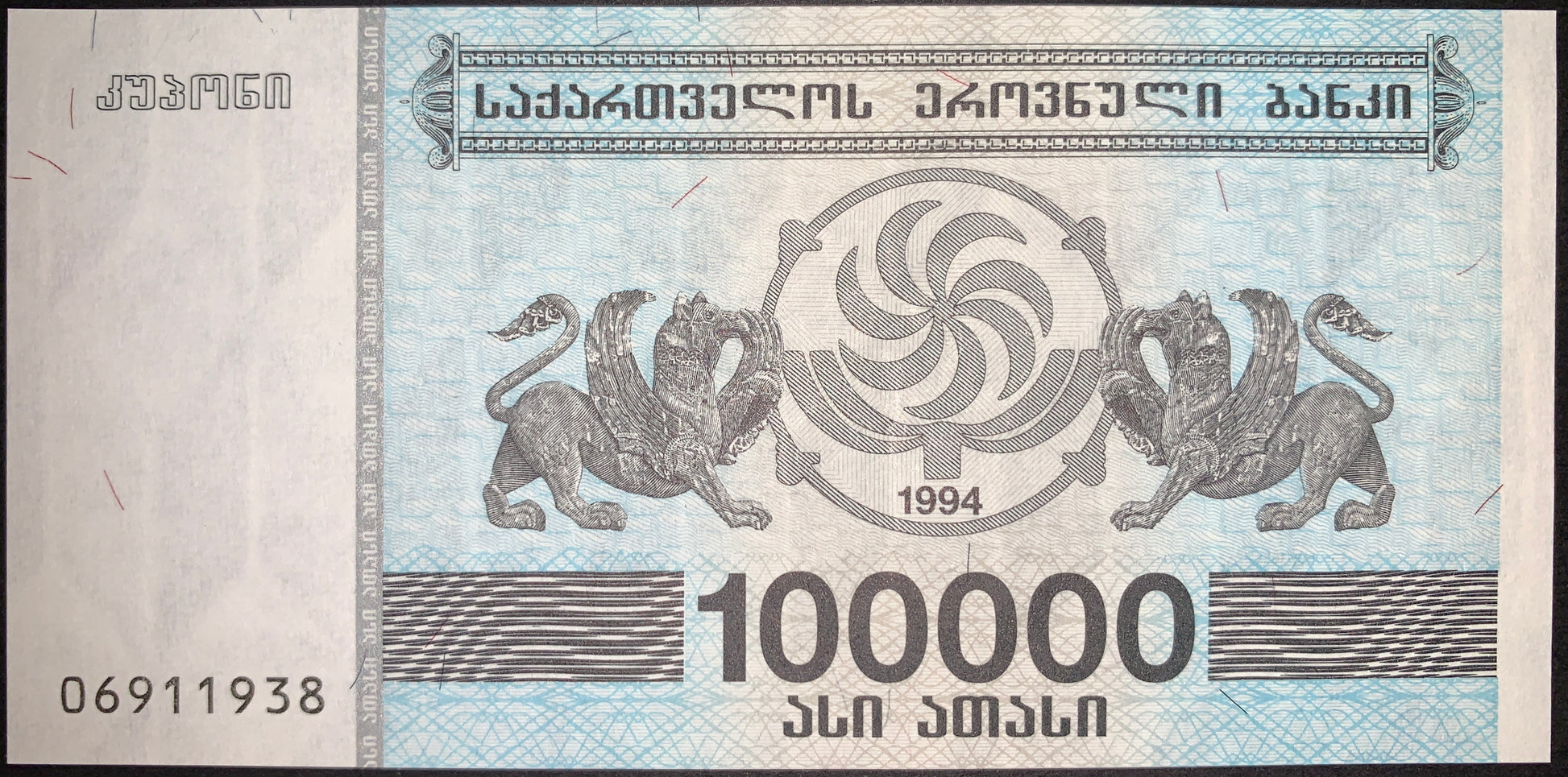 Authentic Georgia 100,000 Kuponi banknote issued during the country's hyperinflation period in the 1990s. Features the National Bank of Georgia inscription, ornamental security patterns, mythological winged creatures flanking a central emblem, and large denomination numerals.