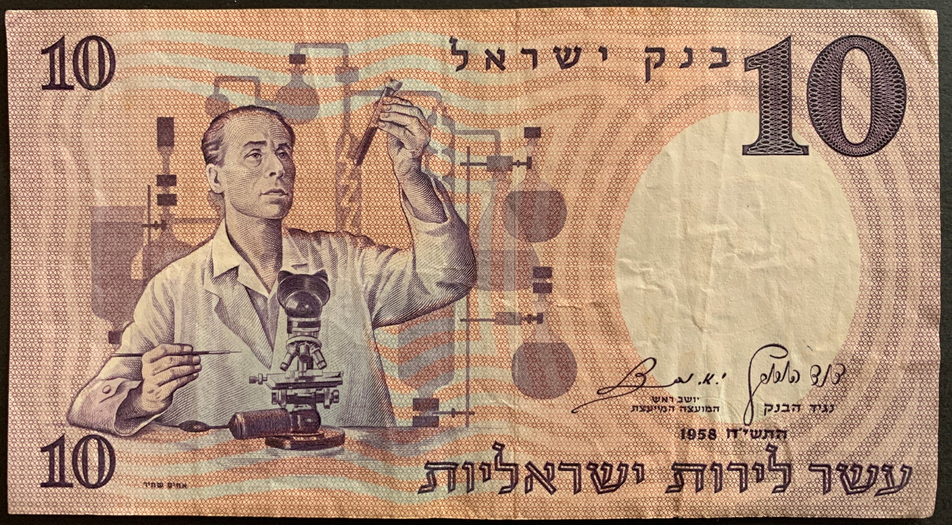 Ten Israeli Pound banknote featuring a scientist with laboratory equipment.