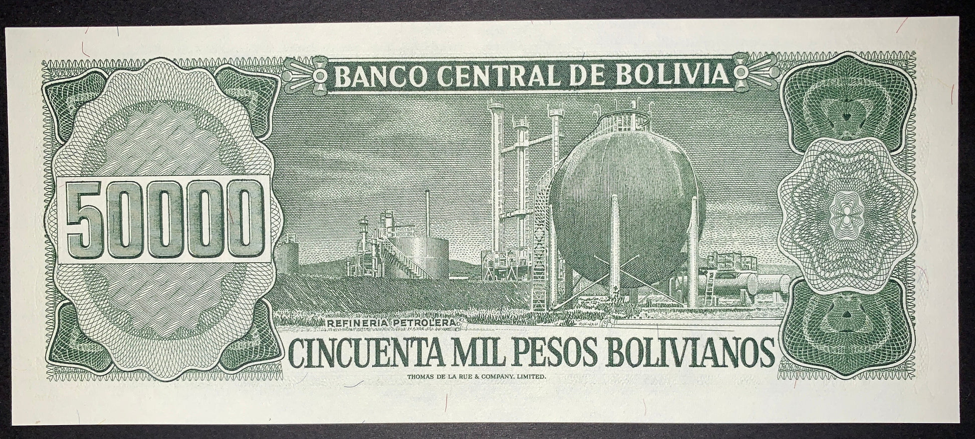 Reverse of an authentic Bolivia 50,000 Pesos Bolivianos banknote, 1984 issue, Pick P-170. Features an industrial petroleum refinery with detailed engraved linework, ornate guilloche patterns, and the large 50,000 denomination.