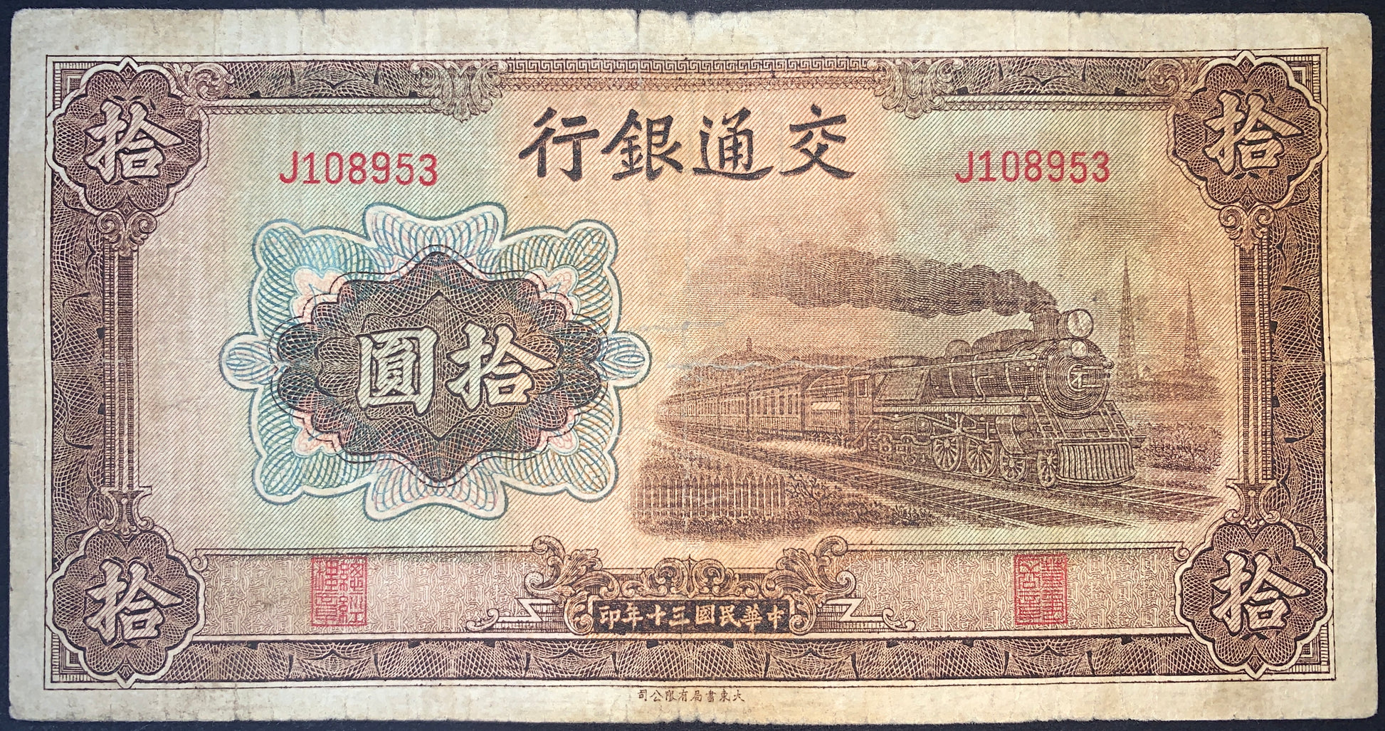 China 10 Yuan 1941 Bank of Communications banknote featuring a detailed steam train in motion, ornate guilloche patterns, Chinese inscriptions, red serial numbers, and finely engraved transportation-themed artwork.