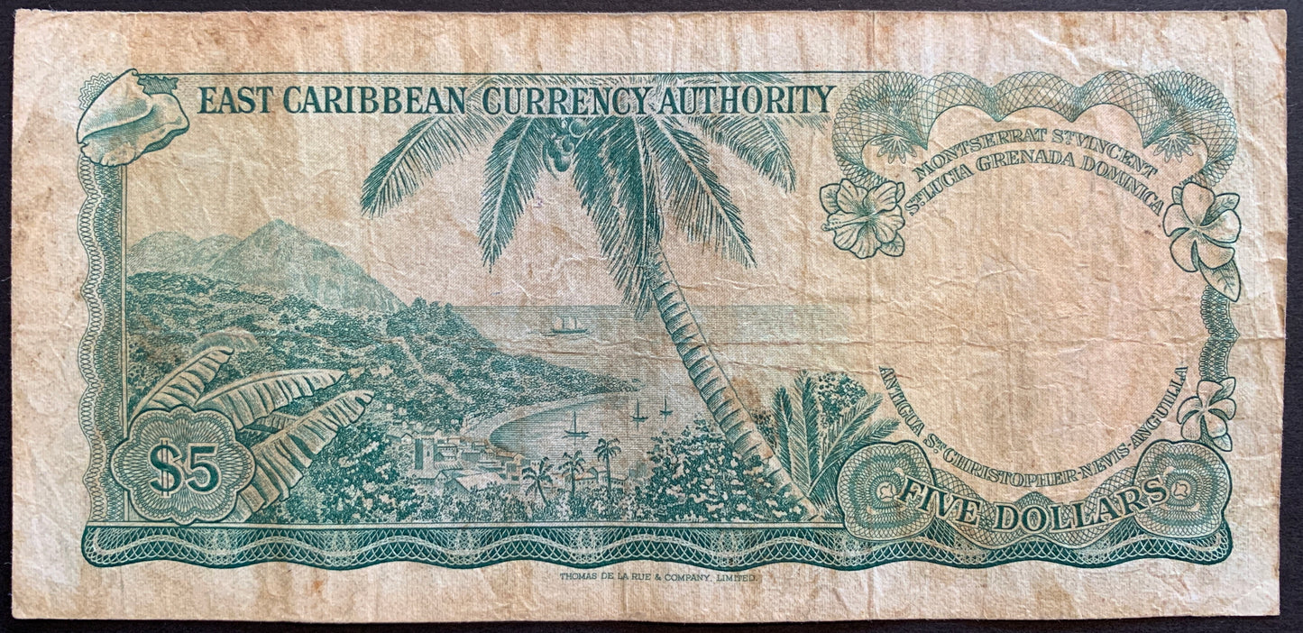 Back of East Caribbean States 5 Dollars ND (1965) P-14h banknote showing landscape with palm trees, harbor, shell, and flowers