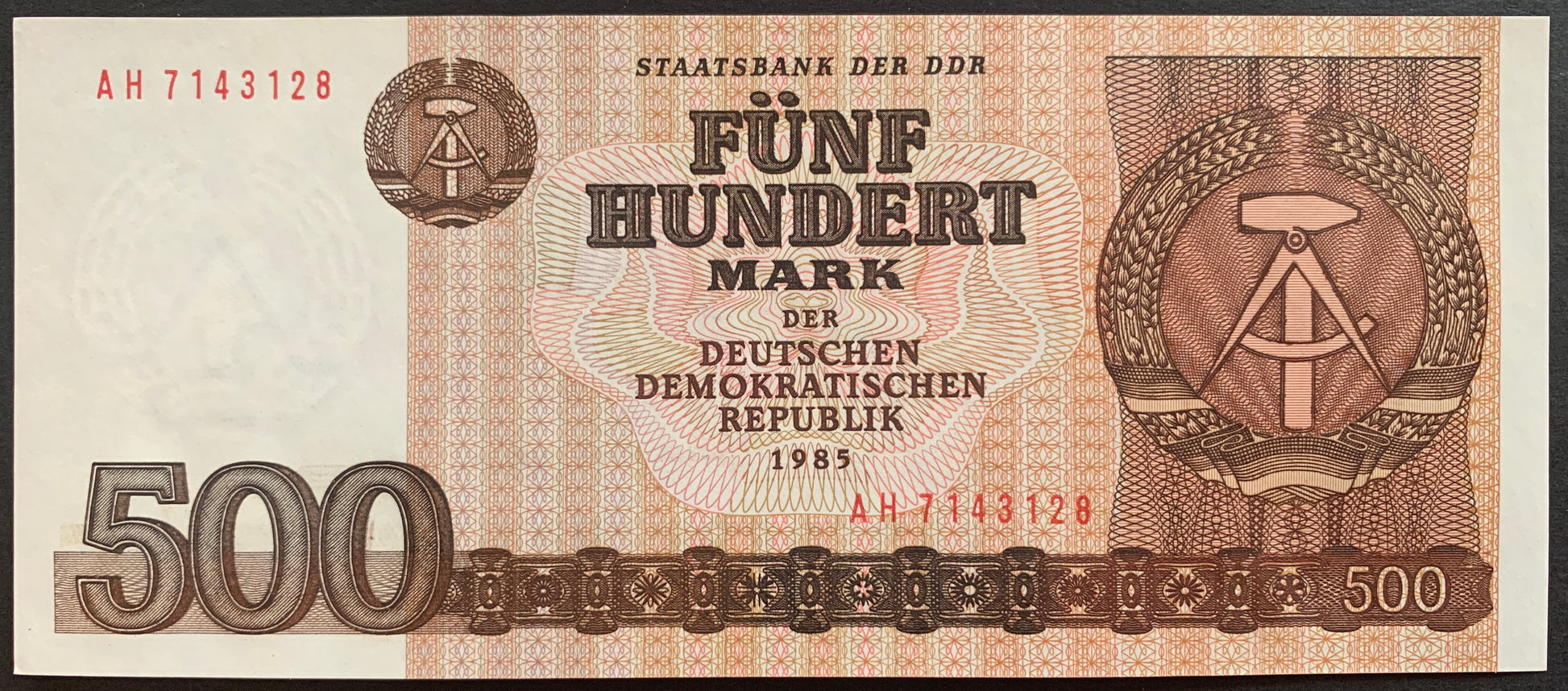 Front view of a crisp, uncirculated 1985 East Germany 500 Mark banknote featuring the DDR national emblem of a hammer and compass surrounded by rye.