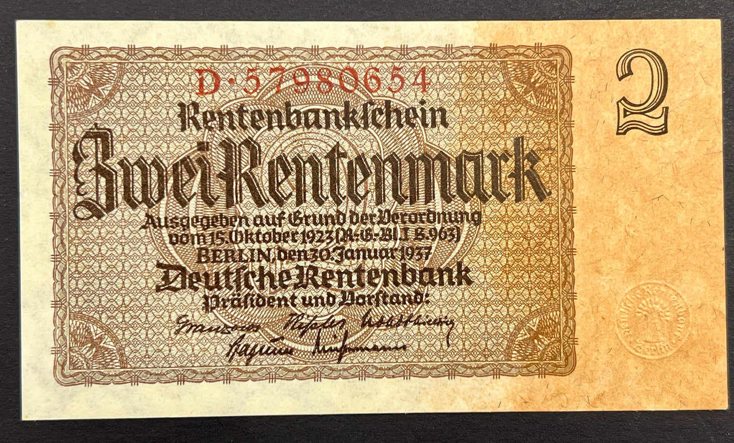 A vintage German Rentenbank 2-mark banknote from 1937, displayed flat against a solid black background. The note features ornate brown and beige security patterns with red serial numbers and black text.