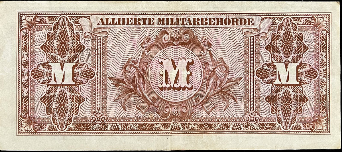 Back view of a 1944 Allied Military Currency 100 Mark banknote reading Alliierte Militärbehörde above three ornate brown M cartouches.