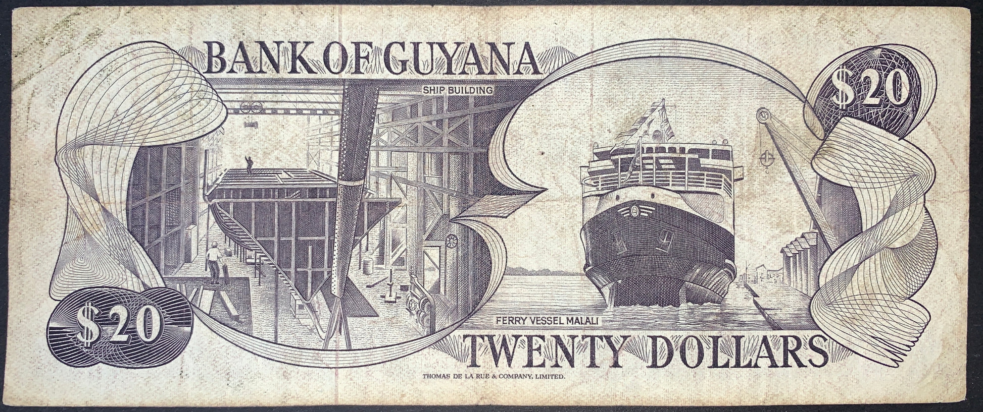Reverse view of a purple Guyana 20-dollar banknote showcasing industrial maritime heritage themes. The left vignette inside a decorative frame depicts a detailed dry dock labeled "SHIP BUILDING," showing workers and the structural hull of a ship under construction. The right vignette portrays the bow view of the "FERRY VESSEL MALALI" navigating the water. The text "BANK OF GUYANA" sits at the top, "TWENTY DOLLARS" at the bottom, with large "$20" denominations set inside intricate flowing line guilloche desi