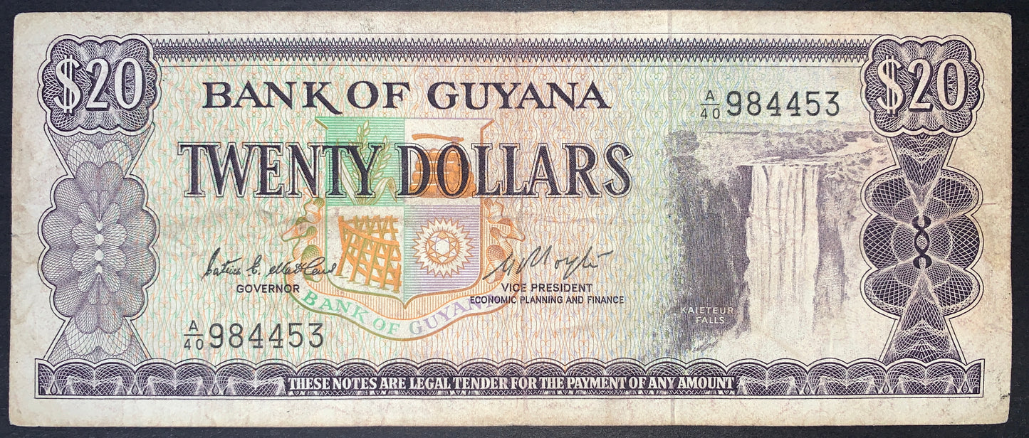 Obverse view of a purple and multi-colored Guyana 20-dollar banknote featuring the majestic Kaieteur Falls on the right side. The text "BANK OF GUYANA" and "TWENTY DOLLARS" is prominently displayed in the center above a large, colorful official Coat of Arms. The serial number A/40 984453 is printed in black ink on the lower-left and upper-right. Intricate purple geometric guilloche patterns and rosettes frame the note, with large "$20" numerals in the top corners.