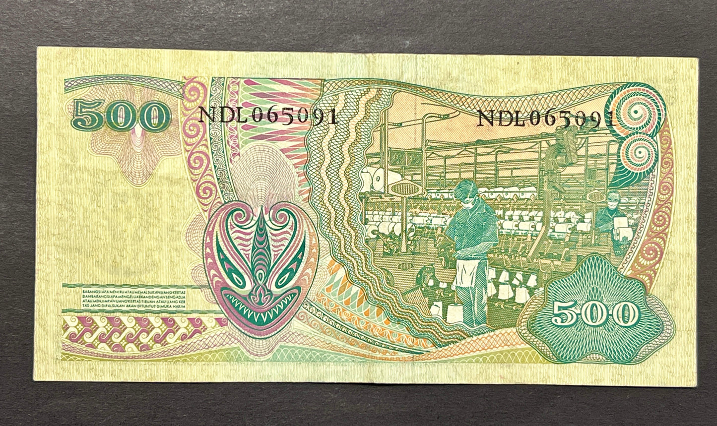 Back view of a 1968 Indonesia 500 Rupiah banknote showcasing a detailed vintage engraving of workers operating machinery inside a textile spinning mill.