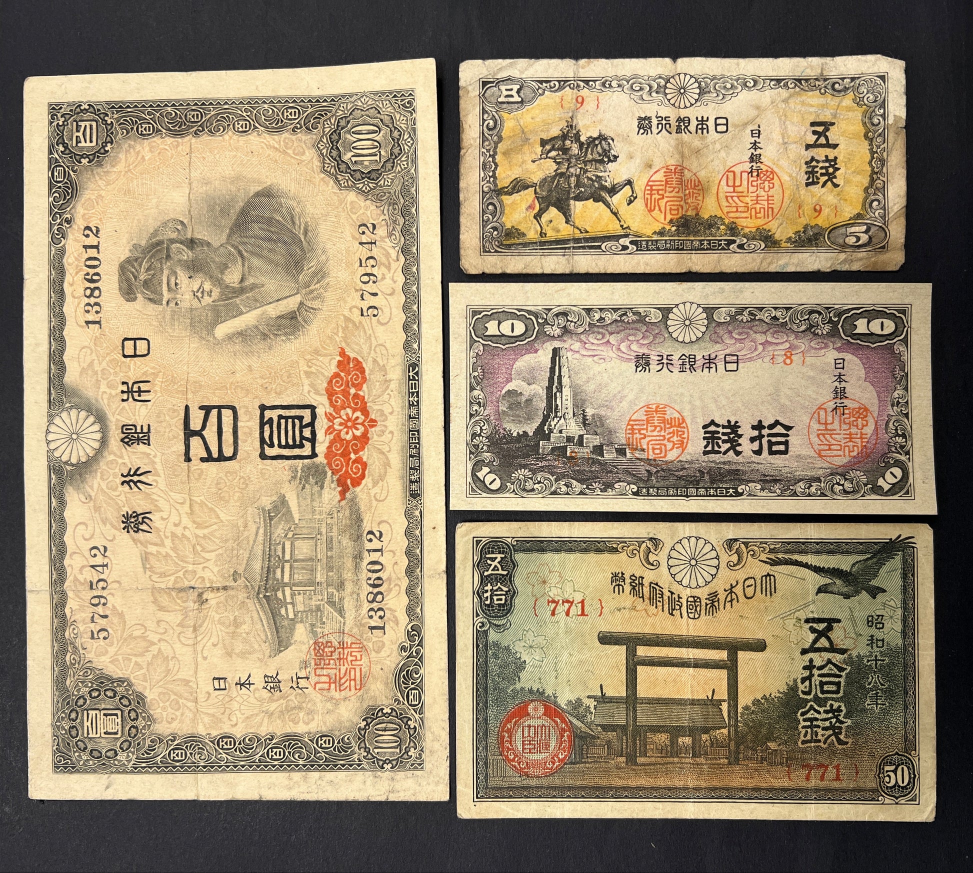 Front view of a vintage Japanese banknote bundle featuring a 1944 100 Yen with Prince Shotoku, and WWII-era 5, 10, and 50 Sen fractional notes with historic shrines and statues.