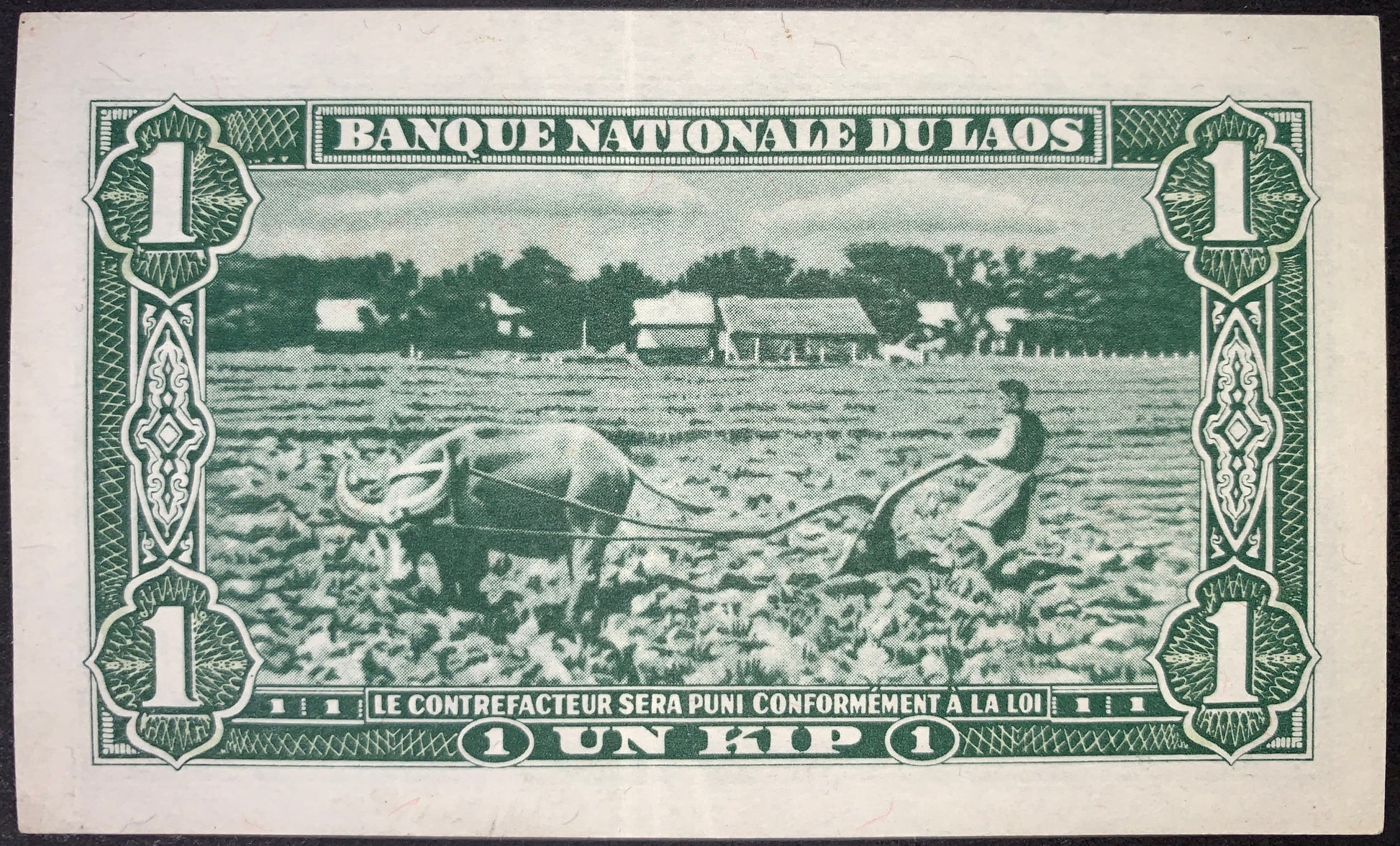 Laos 1 Kip ND (1957–1962) P-1 XF banknote reverse depicting a Lao farmer plowing a rice field with an Asian water buffalo, surrounded by French-influenced guilloche patterns and bilingual Banque Nationale du Laos and Un Kip inscriptions.