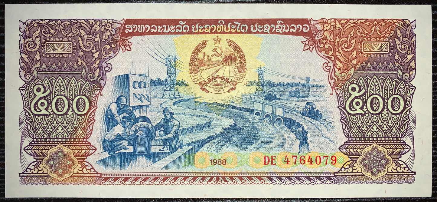 front of Laos  500 Kip 1988 P-31 AUNC collectible vintage asian banknote with workers guiding irrigation systems beneath stretching power lines and tractors