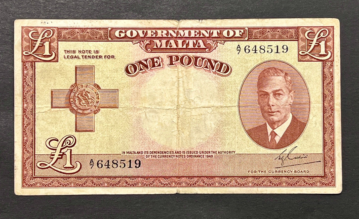 Front view of a vintage 1949 Malta 1 Pound banknote featuring a portrait of King George VI and the George Cross for Gallantry.