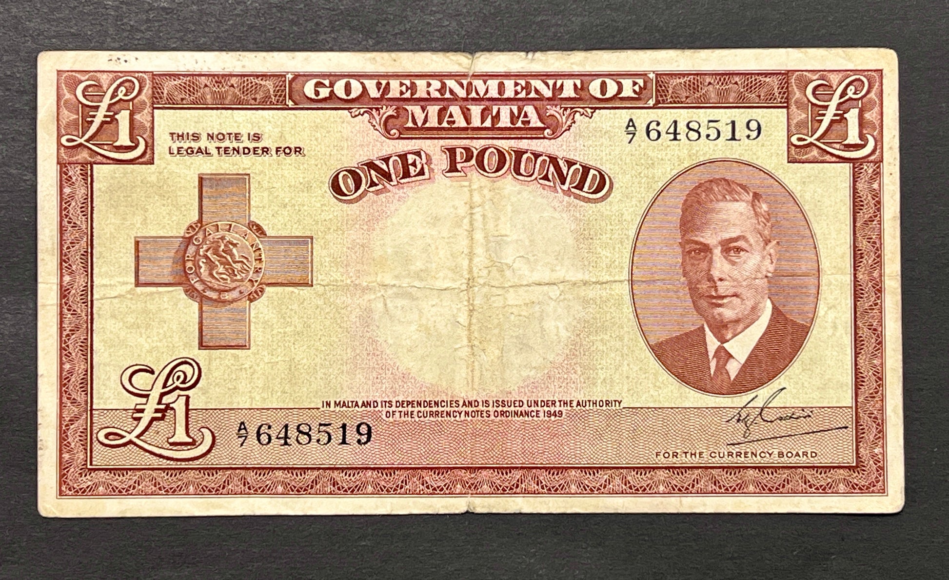 Front view of a vintage 1949 Malta 1 Pound banknote featuring a portrait of King George VI and the George Cross for Gallantry.
