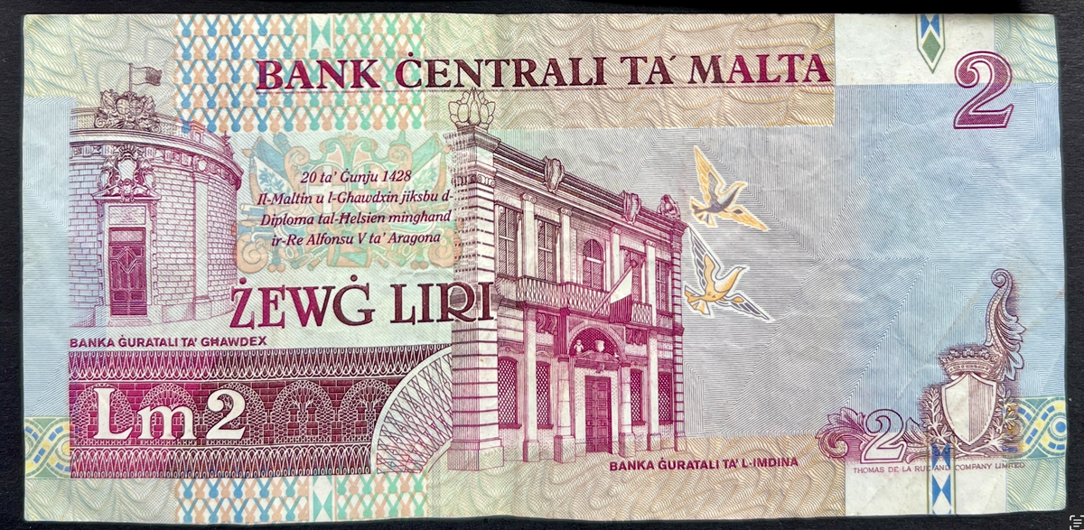 Back view of a vintage 1989 Malta 2 Liri banknote showcasing detailed engravings of the historic Banca Giuratale buildings in Mdina and Gozo.