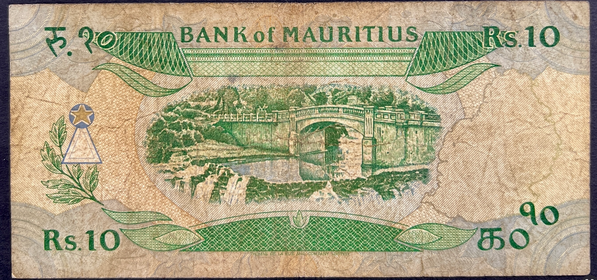Back view of a vintage 1985 Mauritius 10 Rupees banknote showcasing a detailed engraving of a classic stone bridge spanning over a scenic river and waterfall.