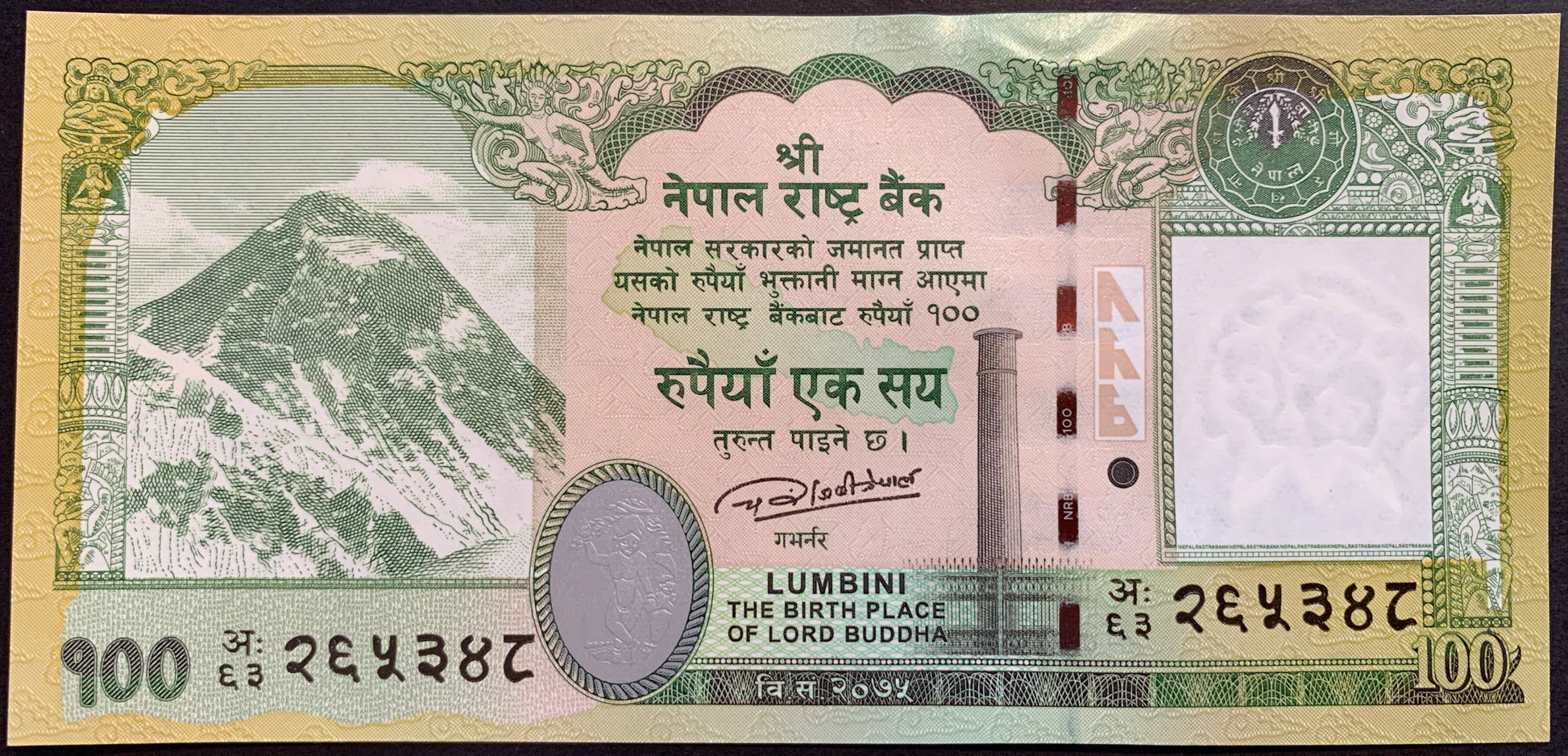 front of Nepal 100 Rupees 2019 P-80b collectible banknote with Mount Everest and Mayadevi in a cameo. Apsaras at the vault. Map outline of Nepal. Ashoka pillar (broken in half) at the Lumbini, the birth place of Buddha