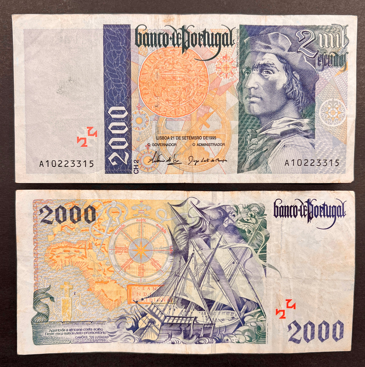 Front view of a circulated 1995 Portugal 2000 Escudos banknote featuring a portrait of explorer Bartolomeu Dias, a navigational astrolabe, and a vintage Cruzado coin. Back view of a vintage 1995 Portugal 2000 Escudos banknote showcasing a detailed engraving of a Portuguese caravel sailing ship navigating rough seas next to a map of Africa.