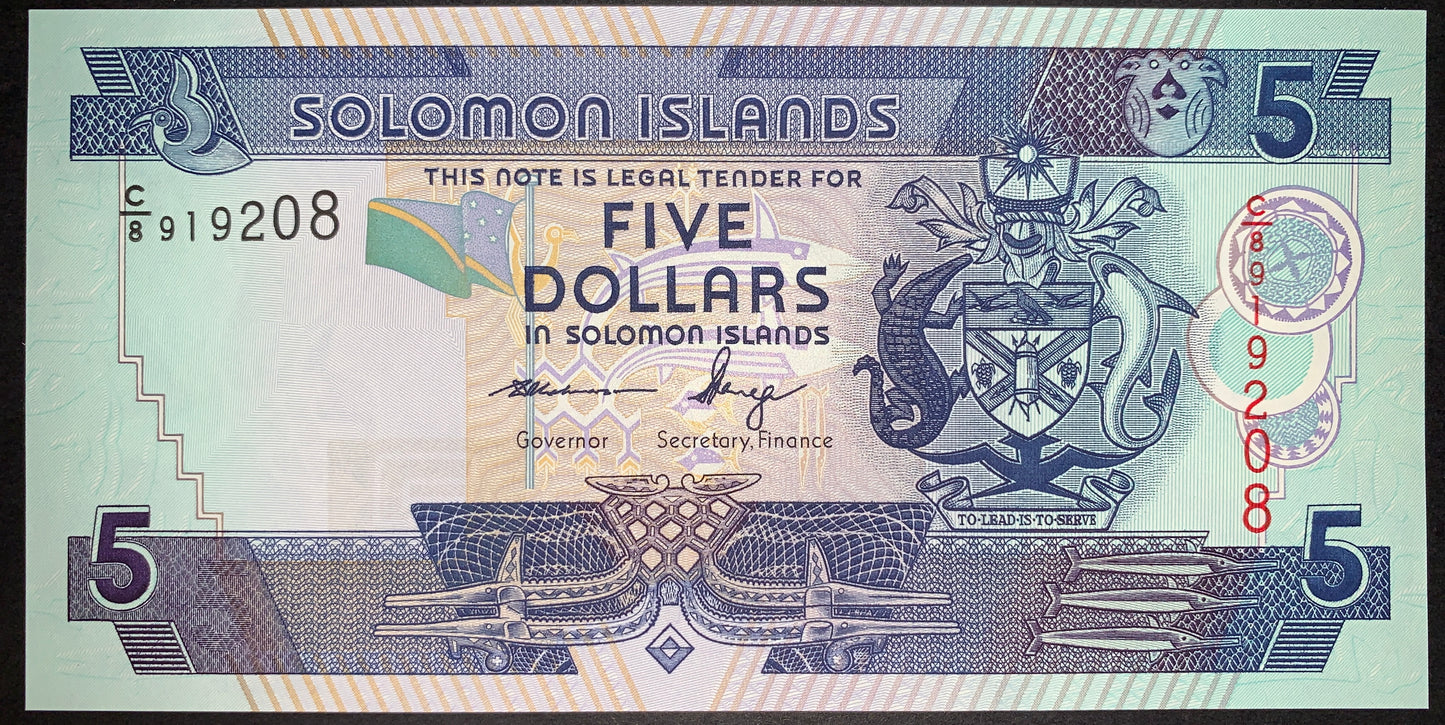 Obverse view of a green and blue Solomon Islands 5-dollar banknote in crisp uncirculated condition. The design features the official national Coat of Arms on the right side, a small waving national flag in the center, and the signatures of Governor Denton H. Rarawa and Secretary of Finance Shadrach Fanega. The horizontal serial number C/8 919208 is printed in black ink on the left, and a vertical serial number is printed in red ink on the right. Intricate geometric tribal patterns and stylized fish motifs b