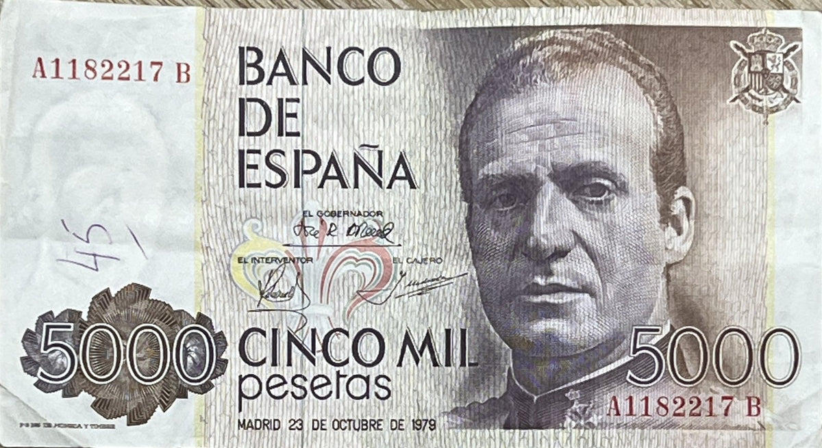Front view of a circulated 1979 Spain 5000 Pesetas banknote featuring a portrait of King Juan Carlos I in uniform and the Spanish royal coat of arms.