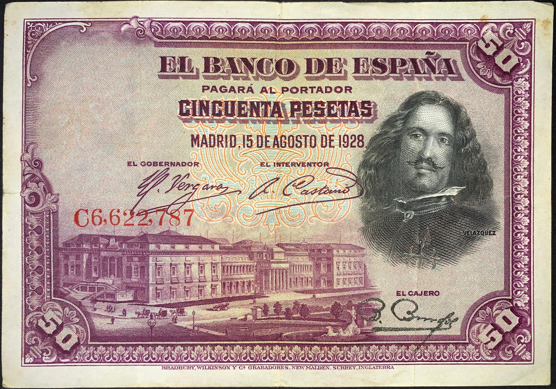 Spain 50 Pesetas banknote dated 15 August 1928 (P-75) featuring a portrait of Diego Velázquez, decorative engraved frame, Banco de España inscriptions, and architectural imagery. Historic Spanish banknote printed in rich purple tones with intricate security patterns.