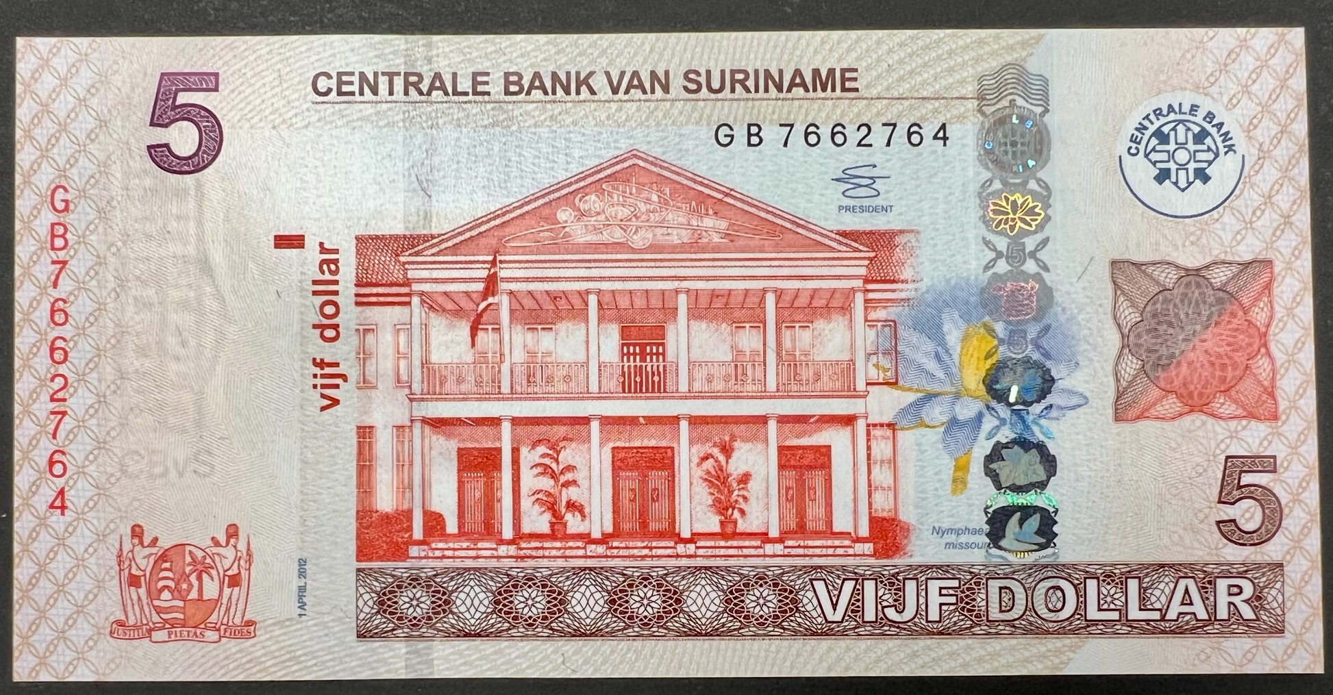 Suriname 5 Dollars banknote P-162b (2012) obverse featuring the Centrale Bank van Suriname headquarters in Paramaribo, holographic security strip with water lily motifs, coat of arms, serial number, Dutch inscriptions, and intricate multicolor security printing.