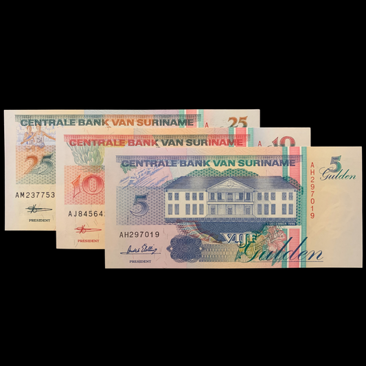 Three Surinamese banknotes of different denominations on a black background