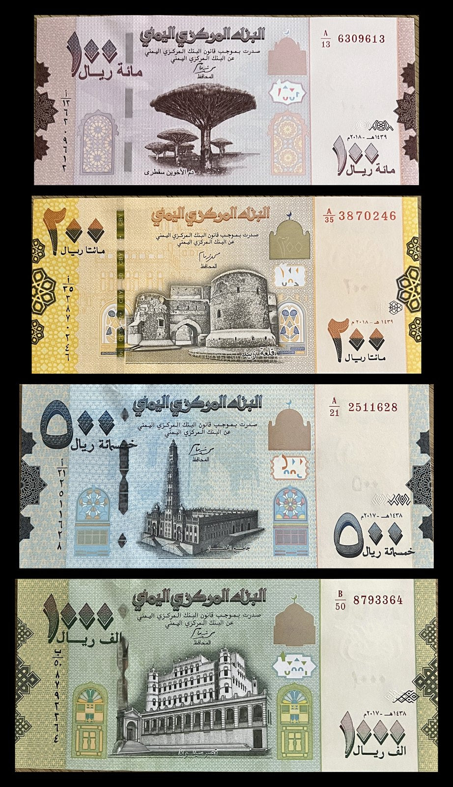 Front view of an uncirculated Yemen 100, 200, 500 and 1000 Rials banknote set featuring Socotra’s dragon’s blood trees, Zabid castle, the Al-Muhdhar Mosque minaret in Tarim and the Sultan’s Palace in Seiyun.