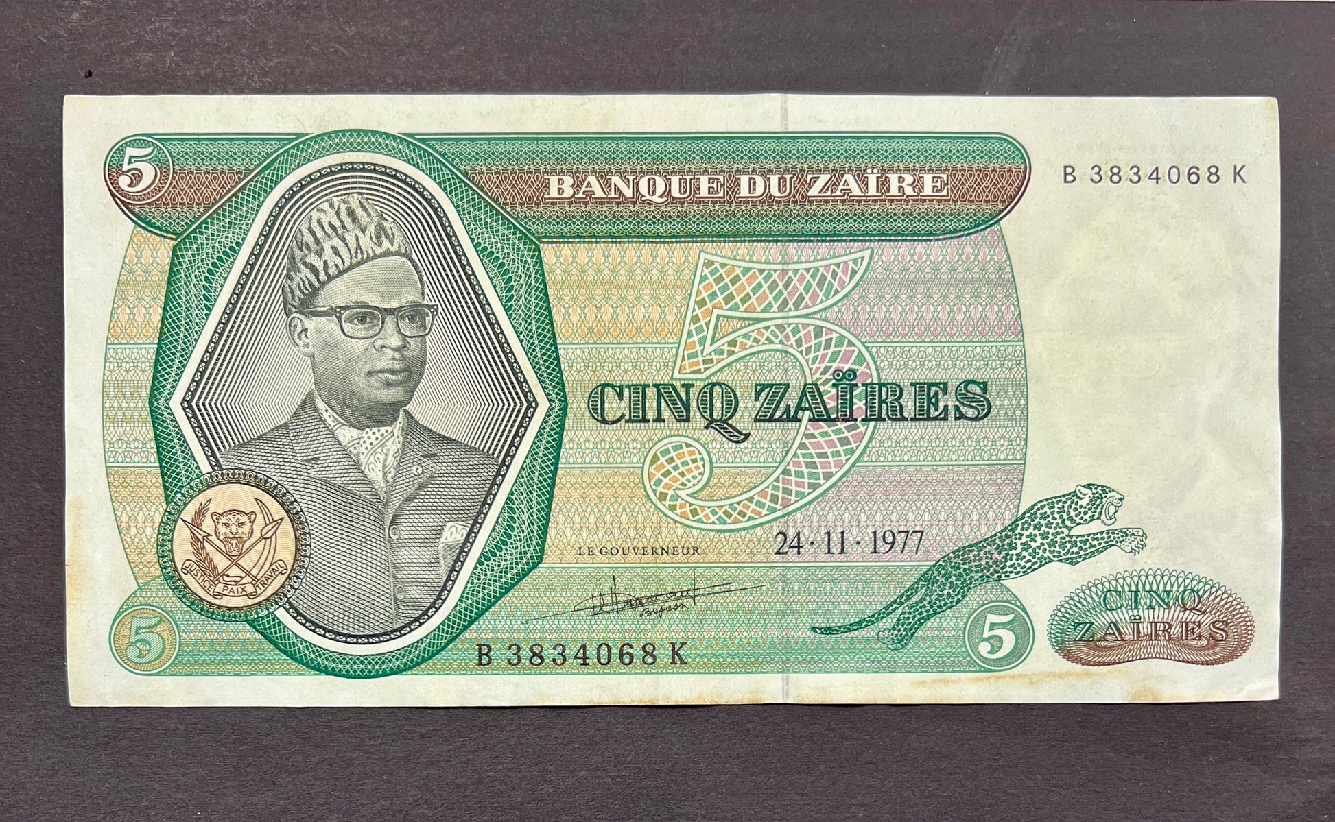 Front view of a circulated 1977 Zaire 5 Zaires banknote featuring a portrait of President Mobutu Sese Seko wearing his signature leopard-print hat, alongside a leaping leopard.