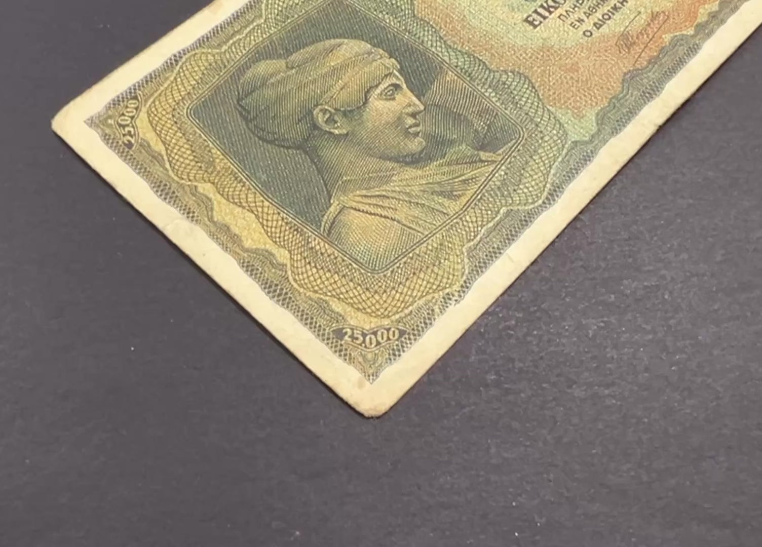 Front view of a circulated 1943 Greece 25000 Drachmai banknote featuring a classical bust of Deidamia and intricate geometric patterns.
