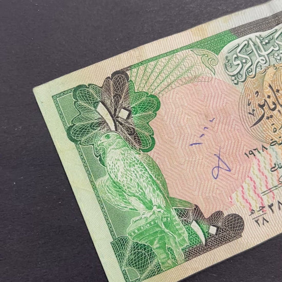 Front view of a circulated 1980s Kuwait 10 Dinars banknote featuring a majestic falcon and the Kuwaiti national coat of arms.