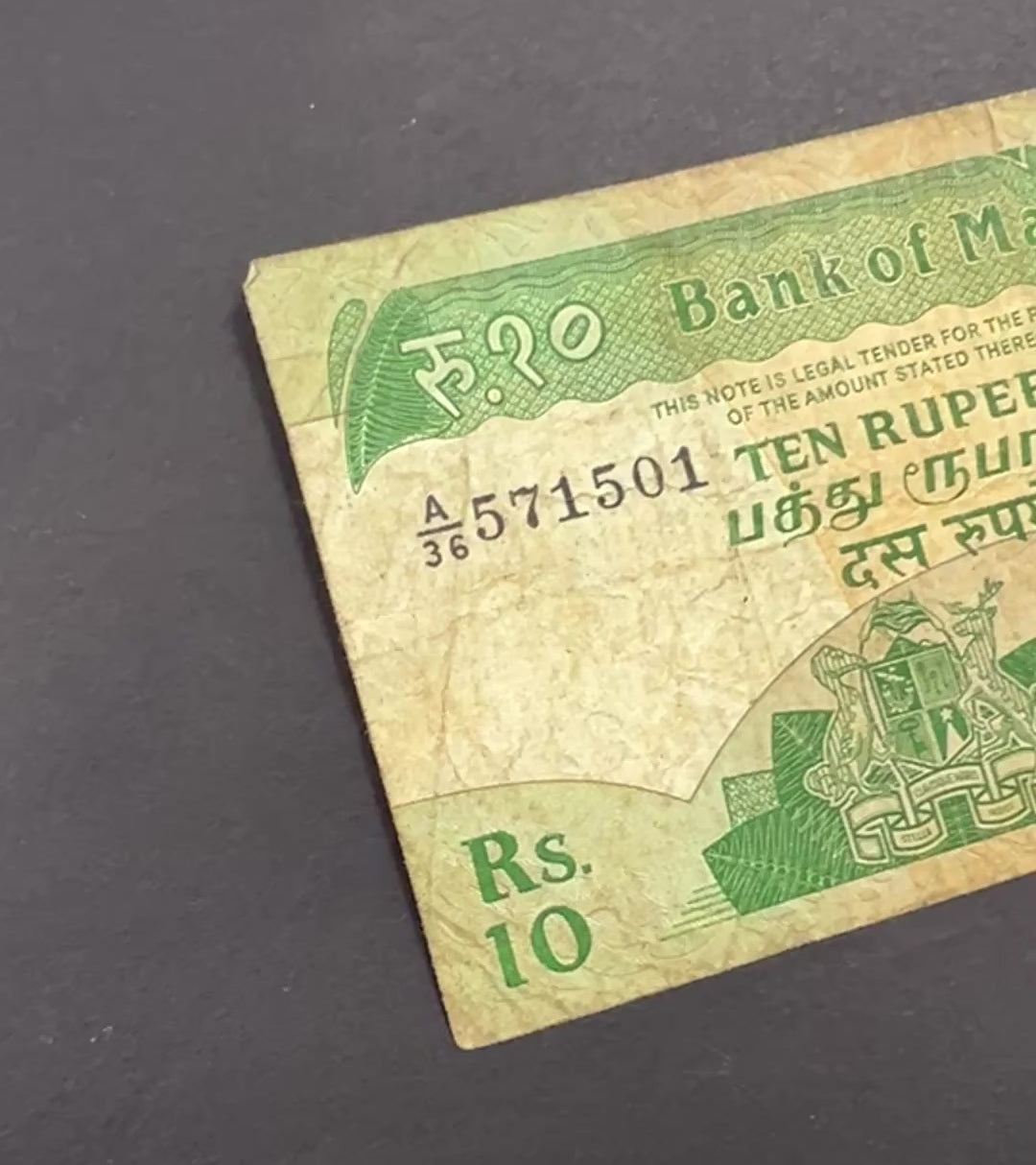 Front view of a circulated 1985 Mauritius 10 Rupees banknote featuring the national coat of arms and the historic Government House building in Port Louis.
